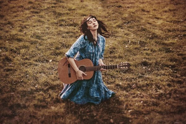 A girl with a guitar on the grass