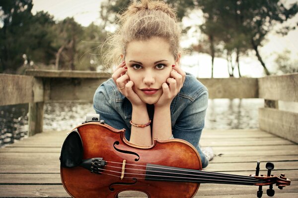 Ragazza con violino in autunno sul molo