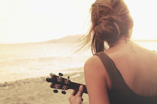 A girl plays guitar by the lake