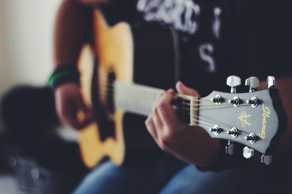 Die Hände sortieren die Saiten auf der Akustikgitarre