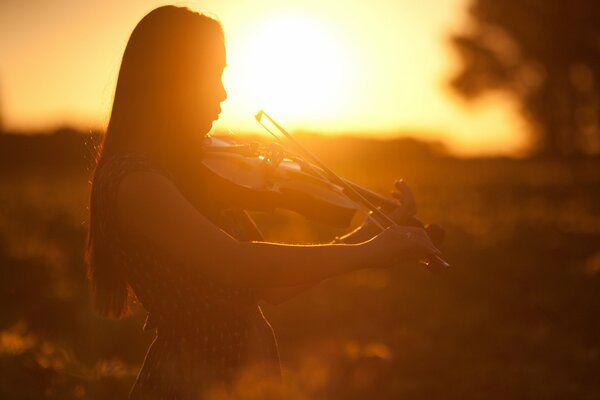 Ragazza che suona il violino alla luce del tramonto