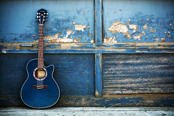 Blue guitar on the background of a peeling wall