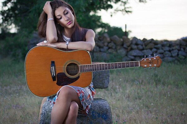 Beautiful girl in the field with a guitar