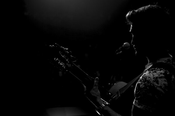 A singer with a guitar in the black darkness