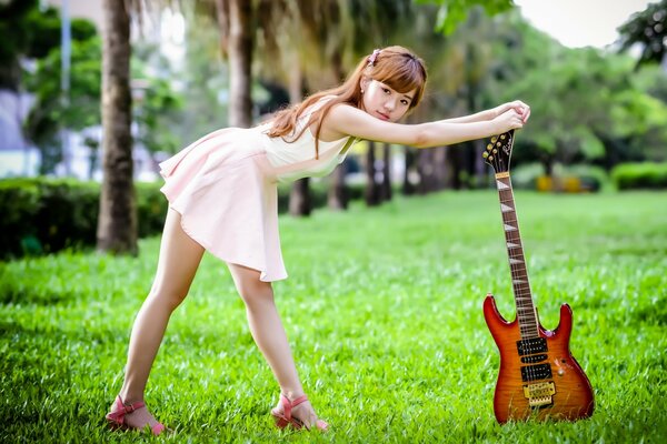 Chica con guitarra verano en la hierba