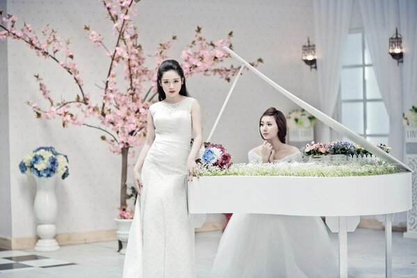 Chicas con vestidos blancos al lado del piano