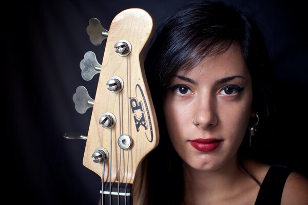 Visage de jeune fille avec manche de guitare sur fond noir