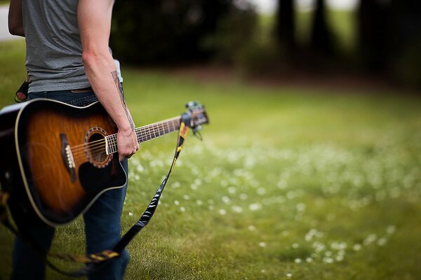 Facet w dżinsach z gitarą w ręku