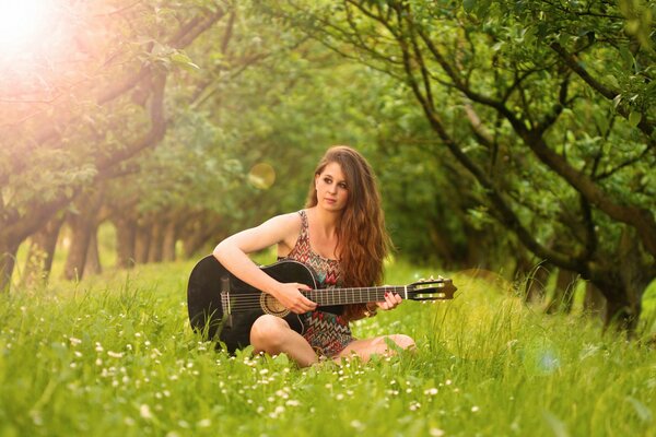 Chica tocando la guitarra en un claro verde