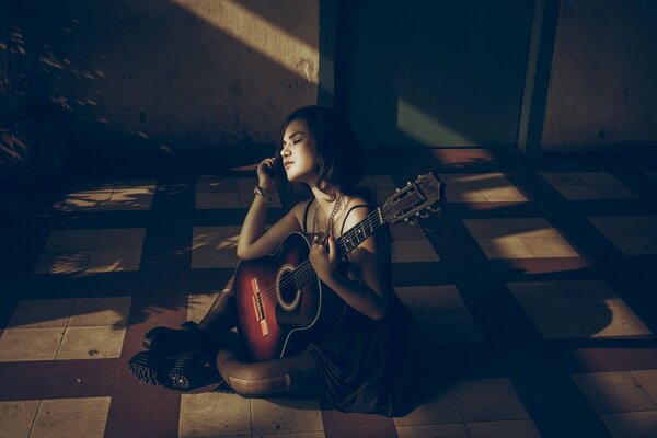 Fille avec une guitare assis sur le sol