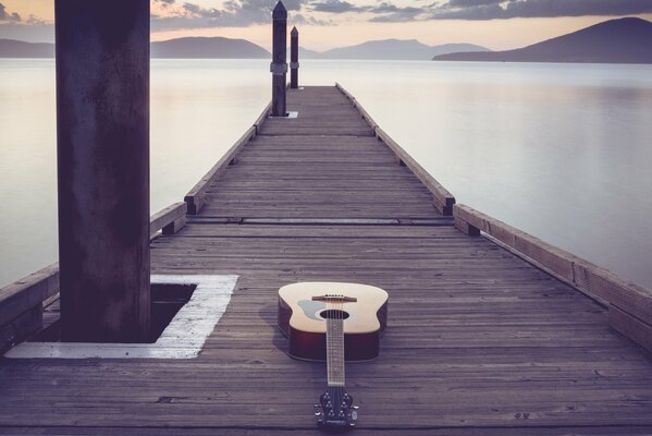 The guitar is lying on a long wooden bridge