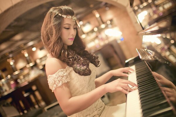 A girl plays the piano in a dress