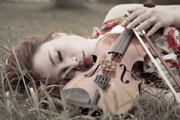 Ragazza sdraiata con un violino sull erba