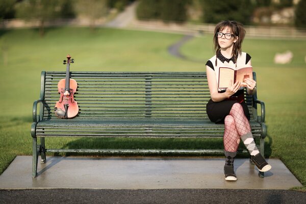 A girl sitting on a bench reading a book