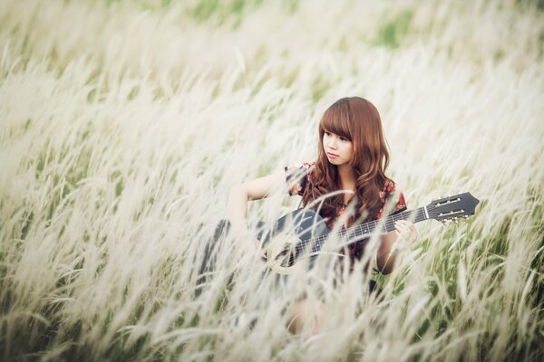 A girl with a guitar in the field