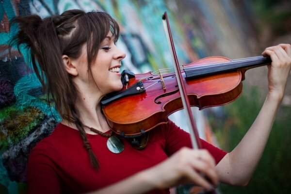 Lindsey Stirling Joue du violon sur fond de mur de graffiti