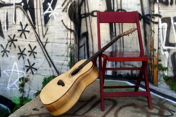 Guitare près d une chaise rouge avec un mur peint