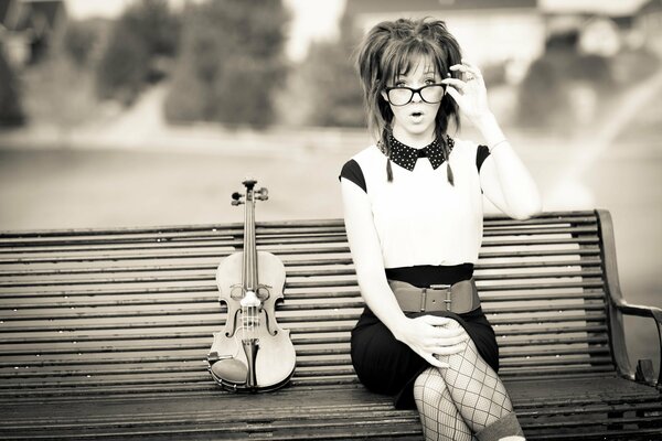 Lindsey Stirling on a bench with a violin