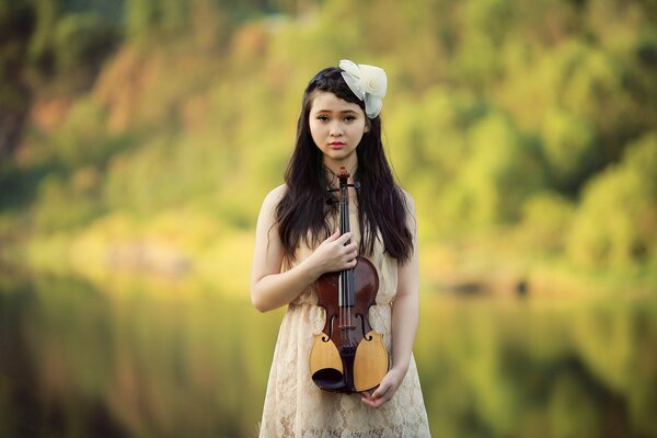 A girl with a violin in nature in summer