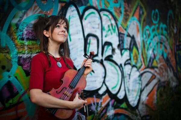 Belleza con un violín en el fondo de una pared pintada