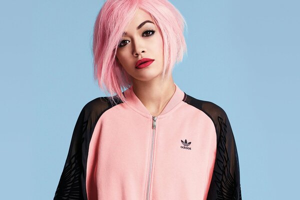 Rita ORA avec des cheveux roses dans un costume adidas