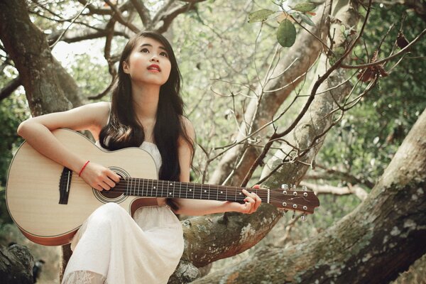 Ragazza asiatica suona la chitarra