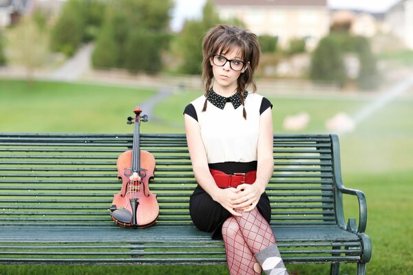 Fille avec violon assis sur le banc