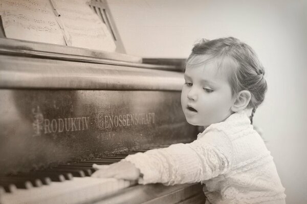 Petite fille appuie sur les touches du piano