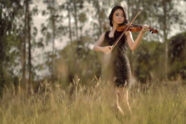 A girl plays the violin in a field