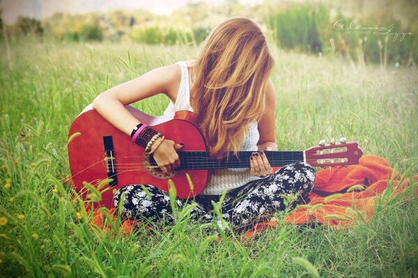 Chica tocando la guitarra en el campo