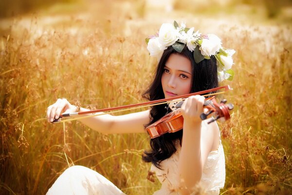 Fille dans une Couronne joue du violon dans un champ