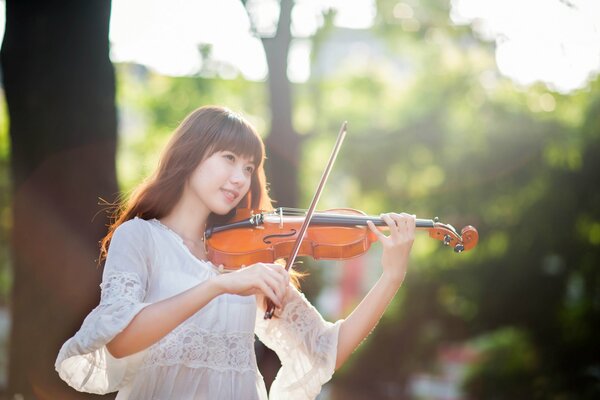 Oriental chica en vestido blanco tocando el violín