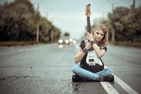 Ragazza con una chitarra in mezzo alla strada