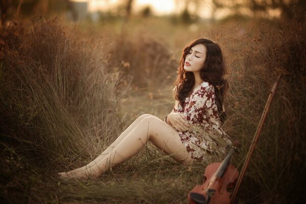 Fille asiatique avec violon dans la nature