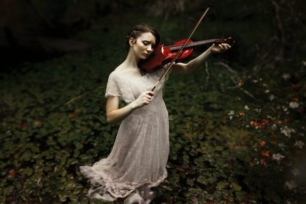 A girl in a long white dress plays the violin