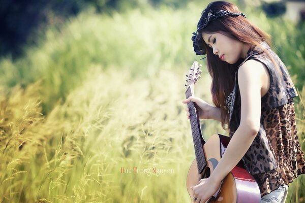 A girl in the field plays the guitar