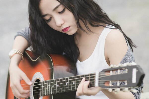 Suonare la chitarra ragazza asiatica con i capelli lunghi