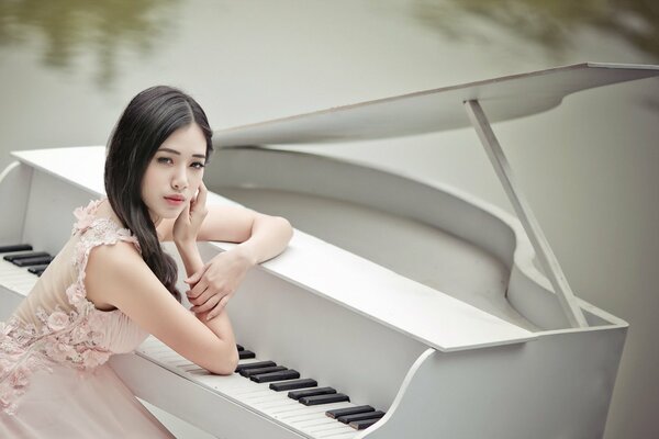 Chica asiática sentada en el piano