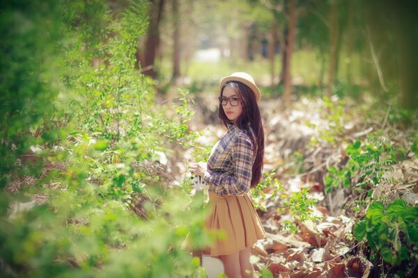 Ragazza in un cappello nella foresta in primavera