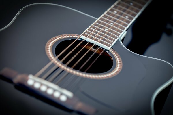 Fotografía macro de una guitarra negra sobre un fondo oscuro