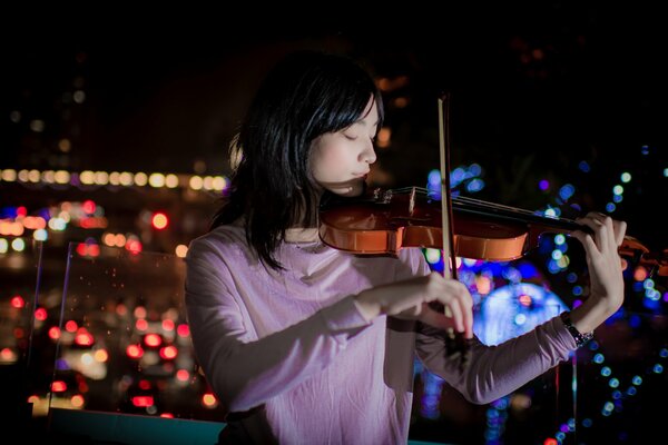 Chica tocando el violín en el fondo de la ciudad de la noche