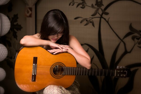 Chica se sienta y abraza la guitarra