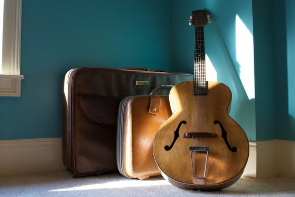 Guitarra y maletas bañadas por la luz del sol