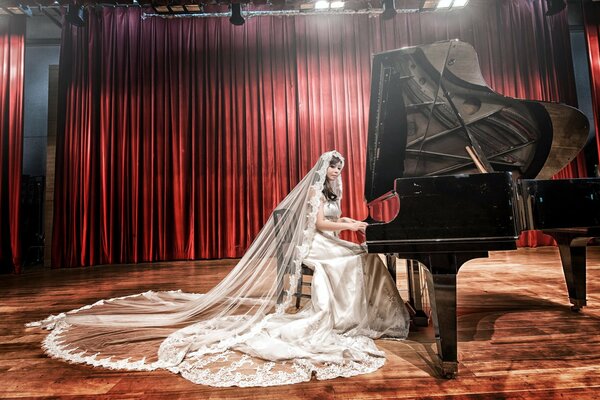 Asian woman in a long white dress plays the piano