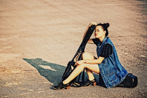 Chica en la calle con una guitarra y una grabadora