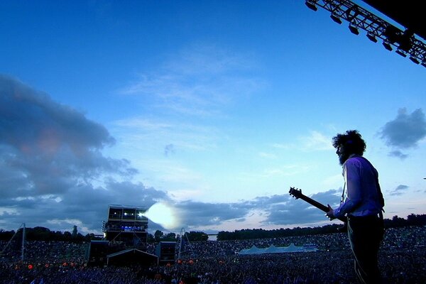 There is a big crowd of people at a rock concert at the stadium