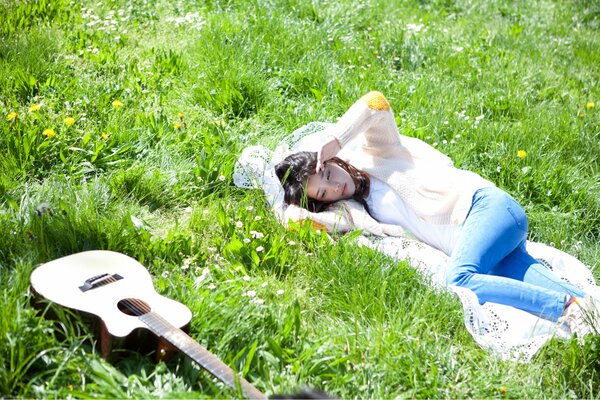 Jeune fille chanteuse se trouve avec une guitare sur l herbe