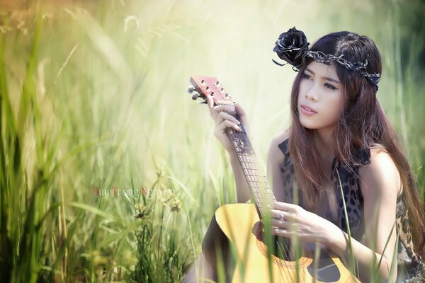 Asian girl with guitar in the field