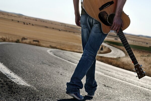 Un uomo con una chitarra cammina lungo la strada