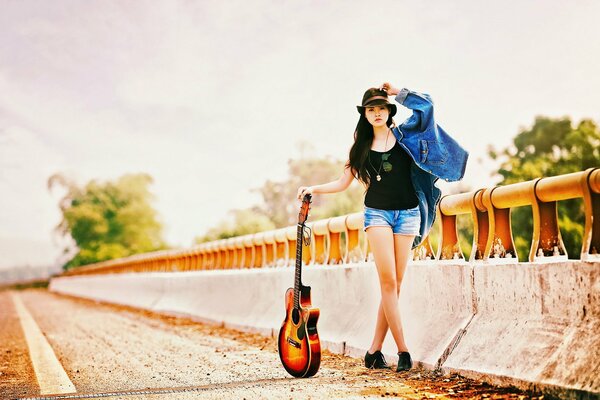 Ragazza sulla strada con la chitarra